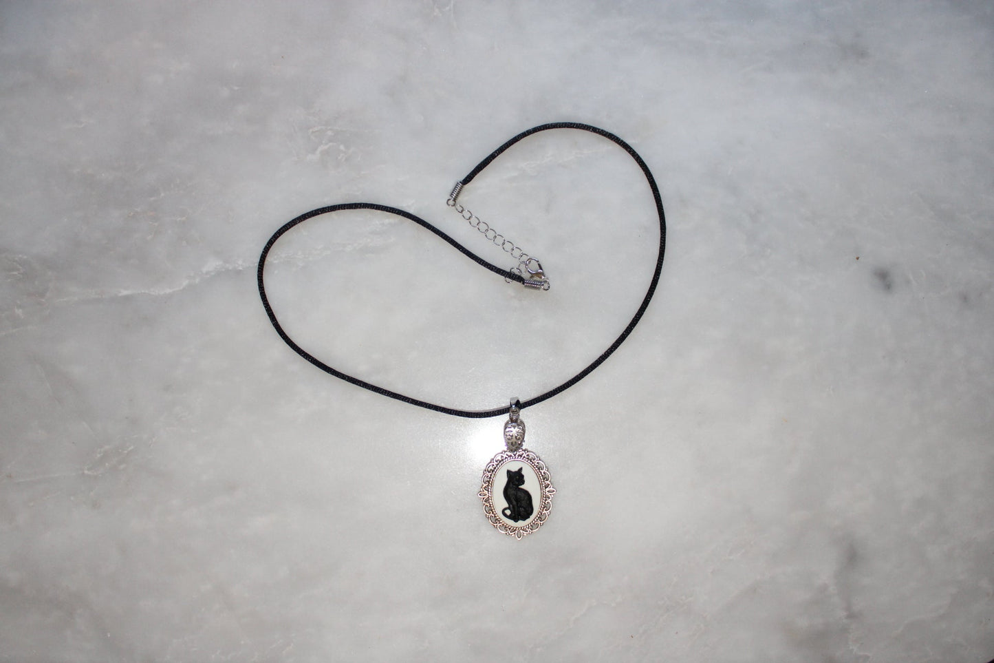 Necklace with a pendant featuring a cat design on a gray surface